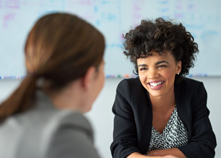 Woman facing another woman who is smiling.