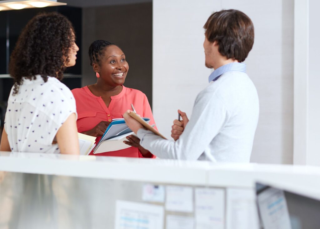Two women and a man engaged in conversation.