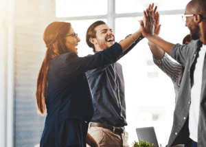 Three [rofessional colleagues standing in a circle for a group high-five.