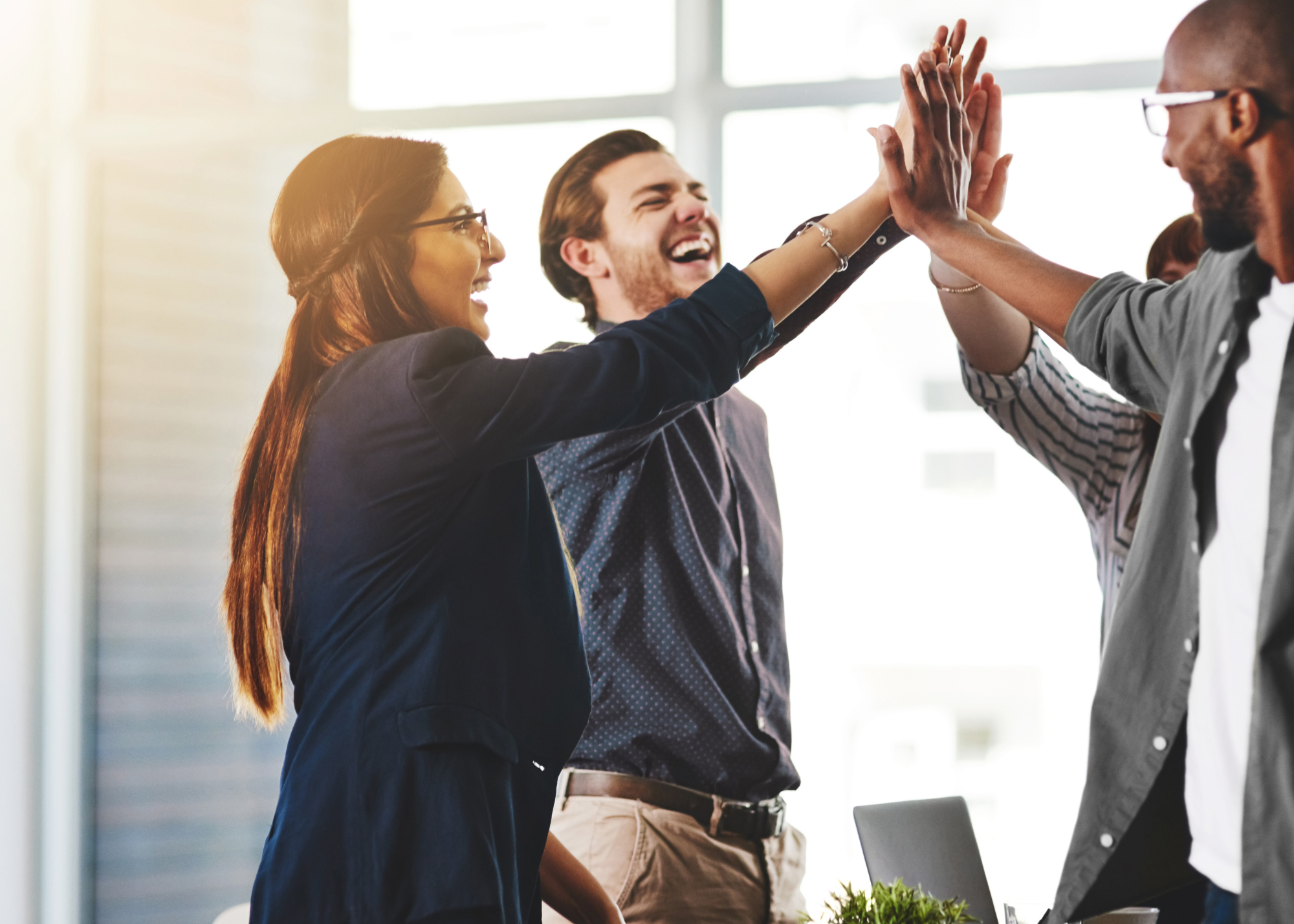 Three [rofessional colleagues standing in a circle for a group high-five.